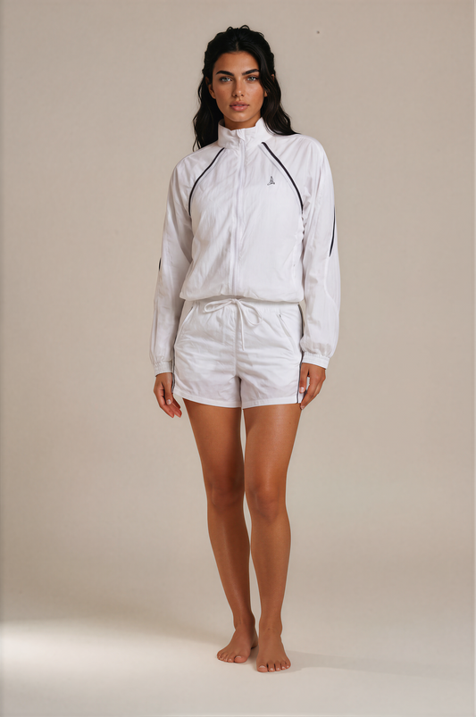 Woman wearing the Aero Court Set in white, lightweight jacket and shorts for padel and tennis