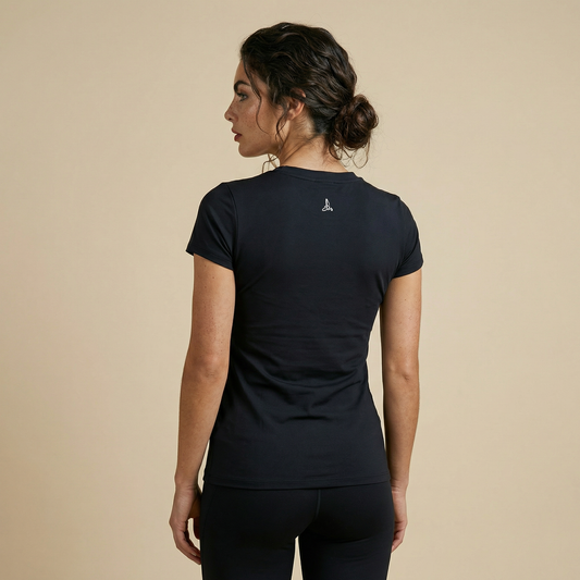 Back view of black short sleeve performance gym top with logo detail at upper back, paired with black leggings in studio setting.