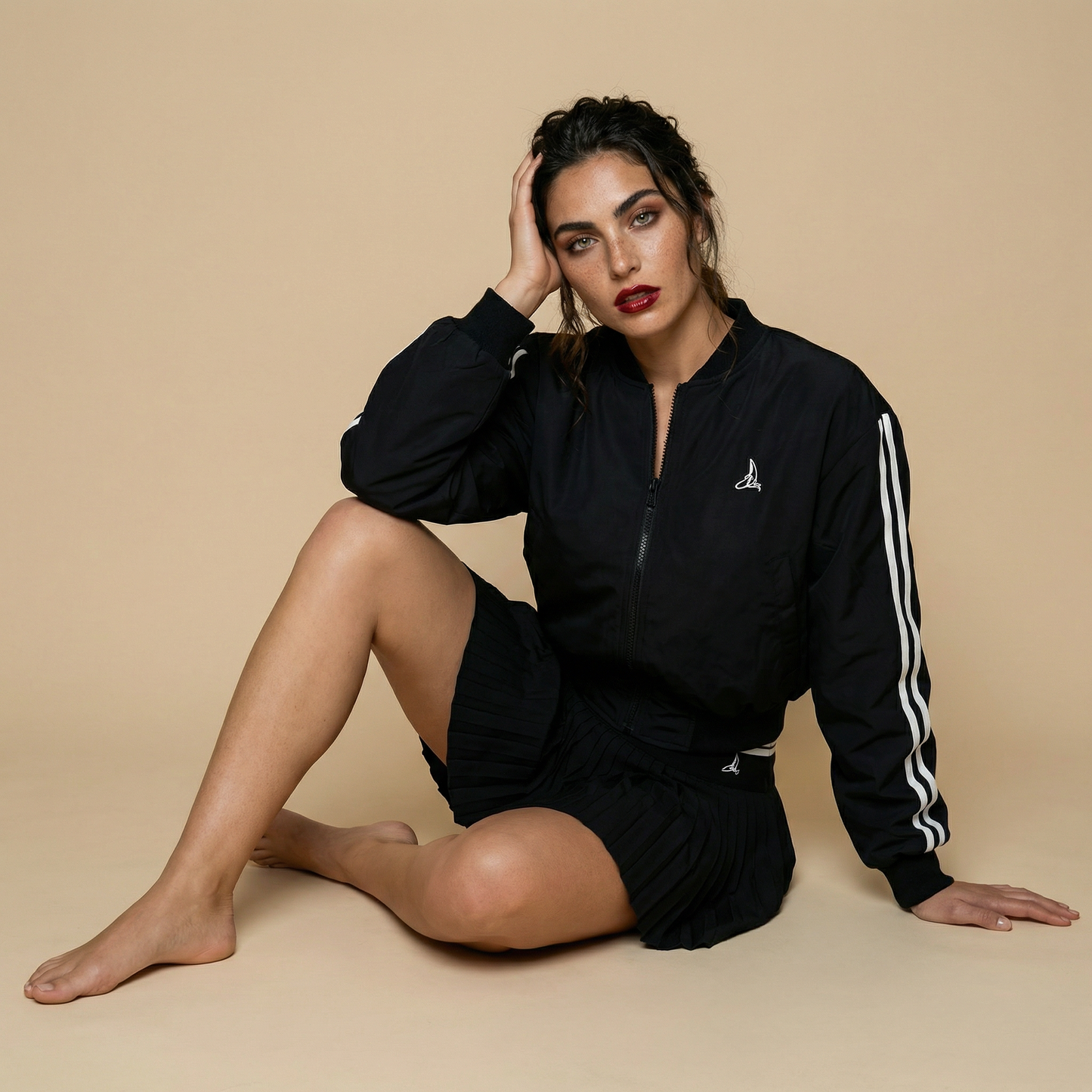 Women’s black sport-luxe padel bomber jacket styled with pleated skirt – Noir Court Bomber by This Is Paria