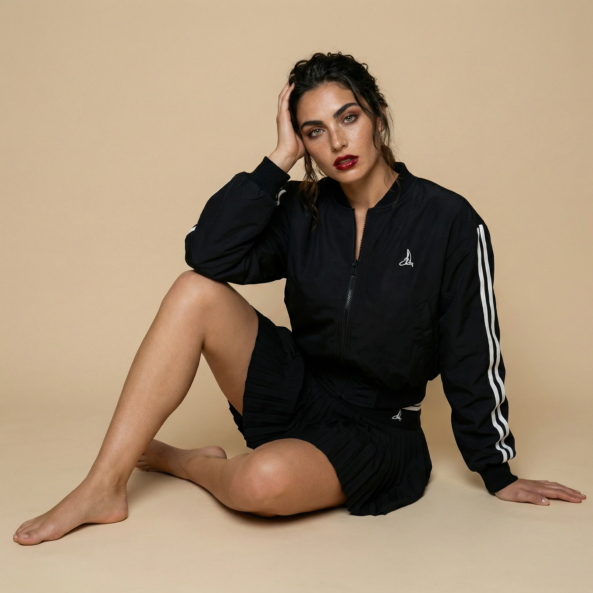Women’s black sport-luxe padel bomber jacket styled with pleated skirt – Noir Court Bomber by This Is Paria