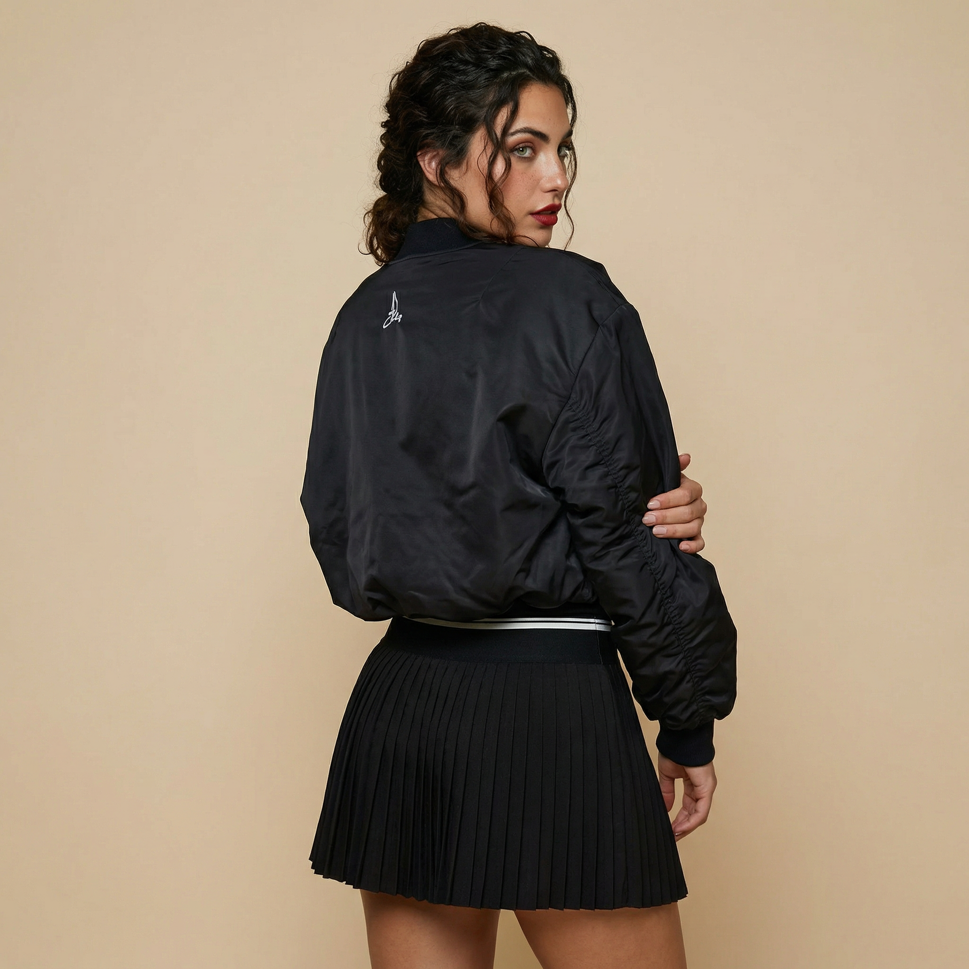 Back view of women’s black padded tennis bomber jacket with embroidered logo – Noir Court Collection